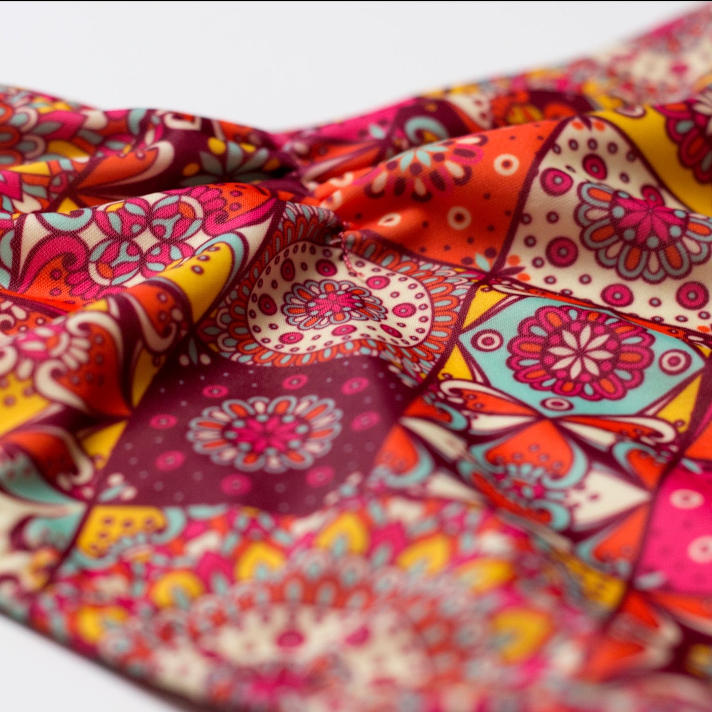 Mandala mintás női bikini alsó anyagának közeli képe, részletes színes minta és textúra, ráncolt és gumiírozott középrész fókuszban, fehér háttéren.