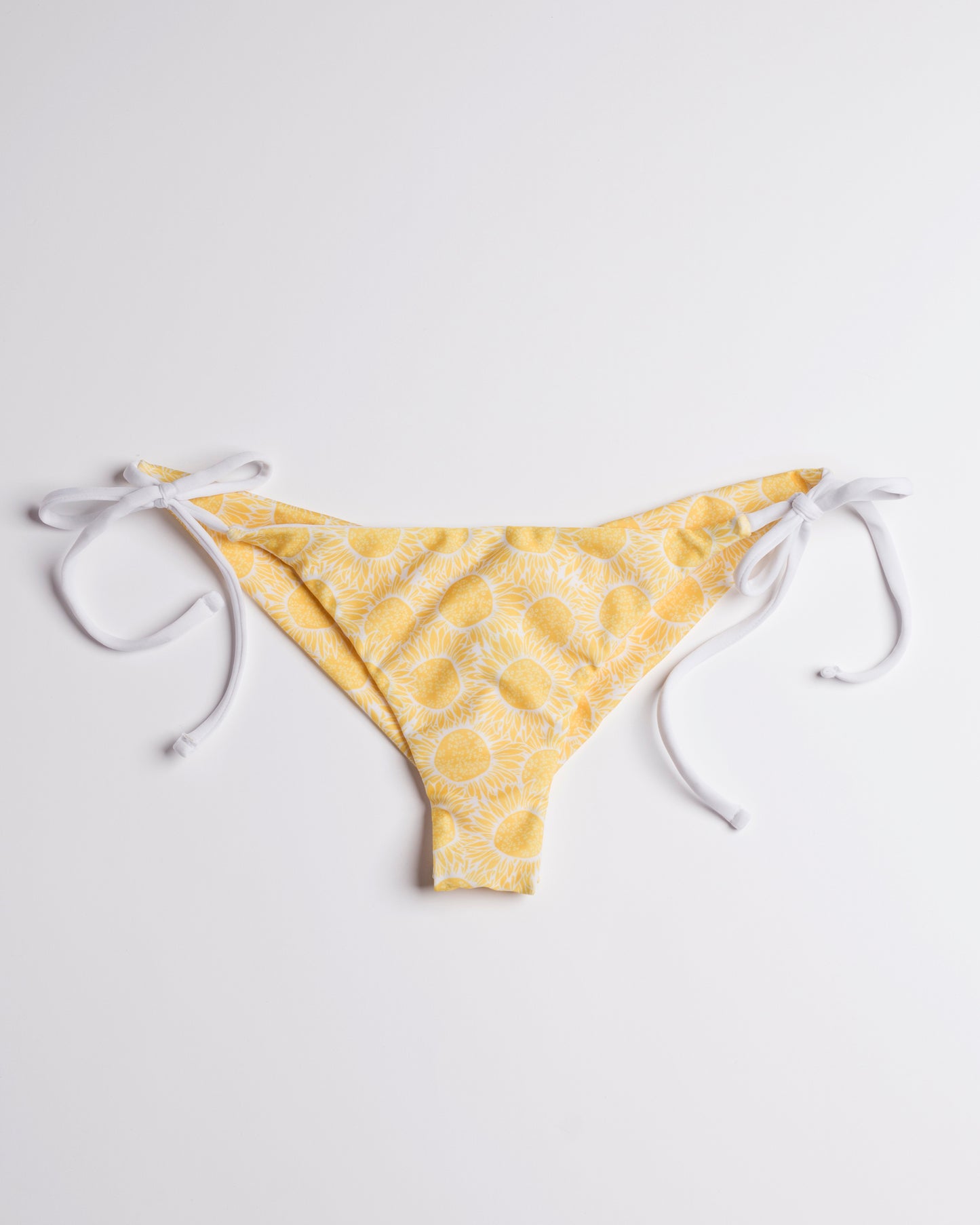 Napraforgó mintás brazil bikini alsó fehér megkötőkkel, leterítve, előről, fehér háttéren