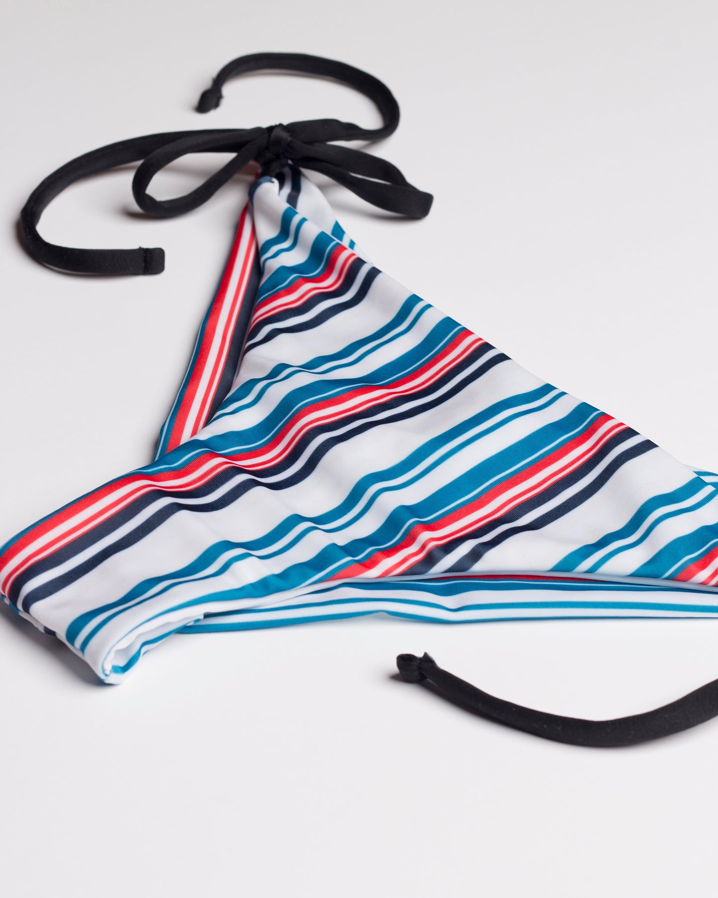Navalang kék és vörös csíkos megkötős brazil bikini alsó, fekete pántokkal, közelről és oldalról, fehér háttéren