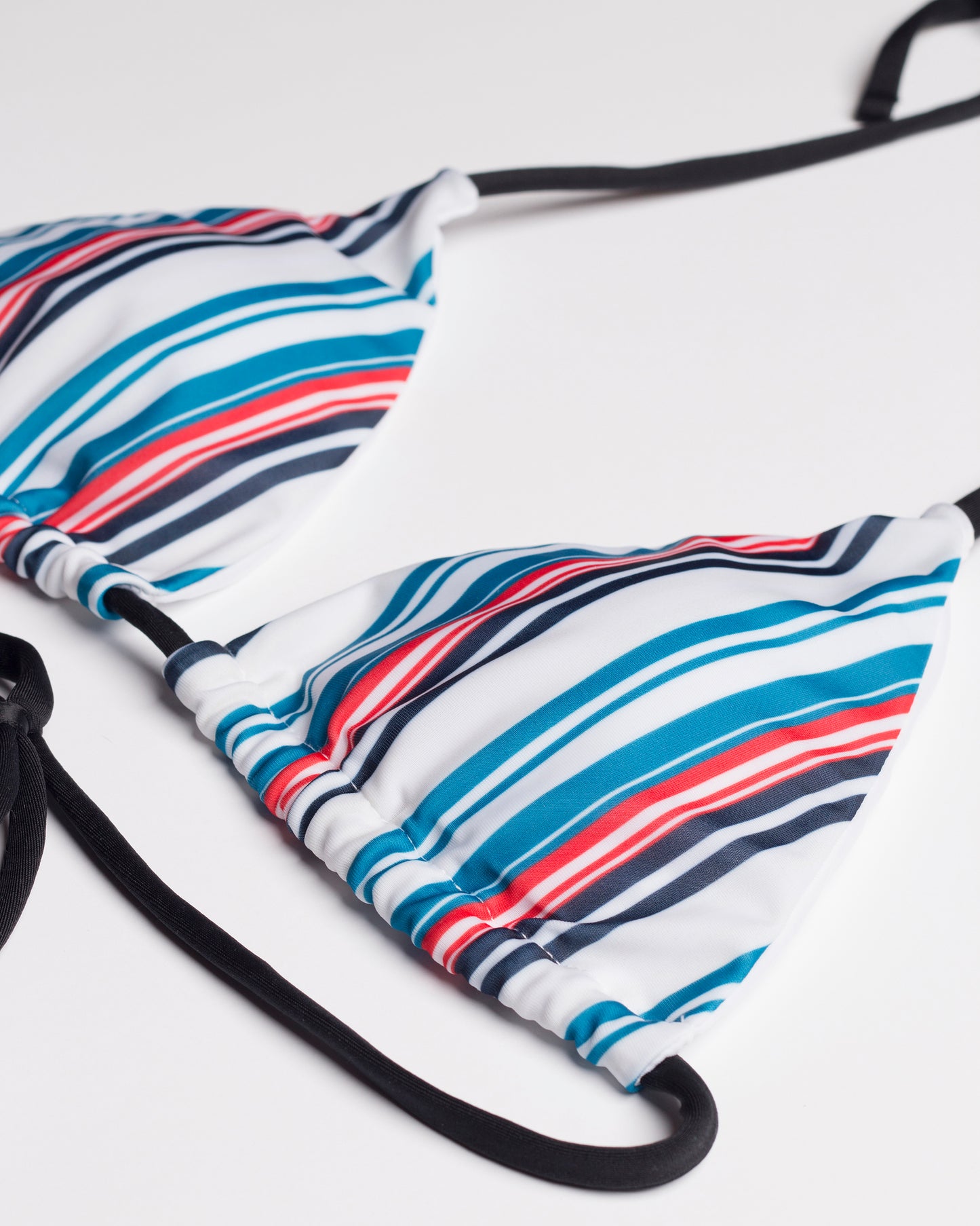 Kék csíkos kivehető szivacsos háromszög bikini felső fekete pántokkal közelről, fehér háttéren