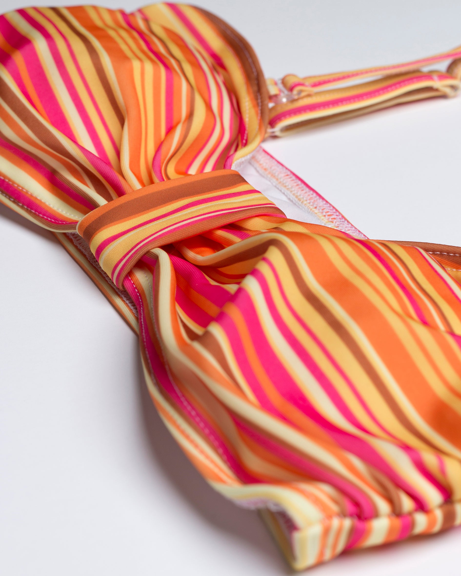 Navalang pink és narancsos élénk színű levehető pántos bandeau bikini felső közeli képe az anyag mintázatáról és a varrásokról
