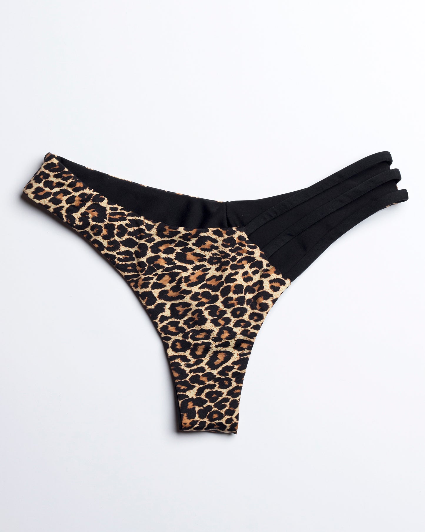 Leopárd mintás brazil bikini alsó fekete asszimetrikus pántokkal elölről fotózva, fehér háttéren.