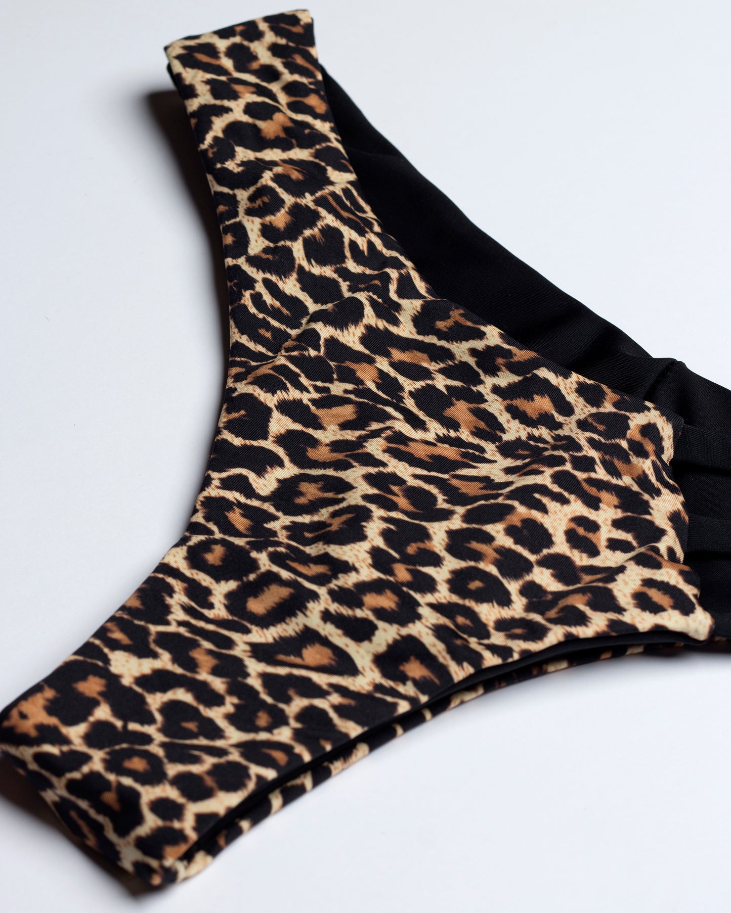 Leopárd mintás brazil bikini alsó, oldalról és ferdén fotózva, fehér háttéren.