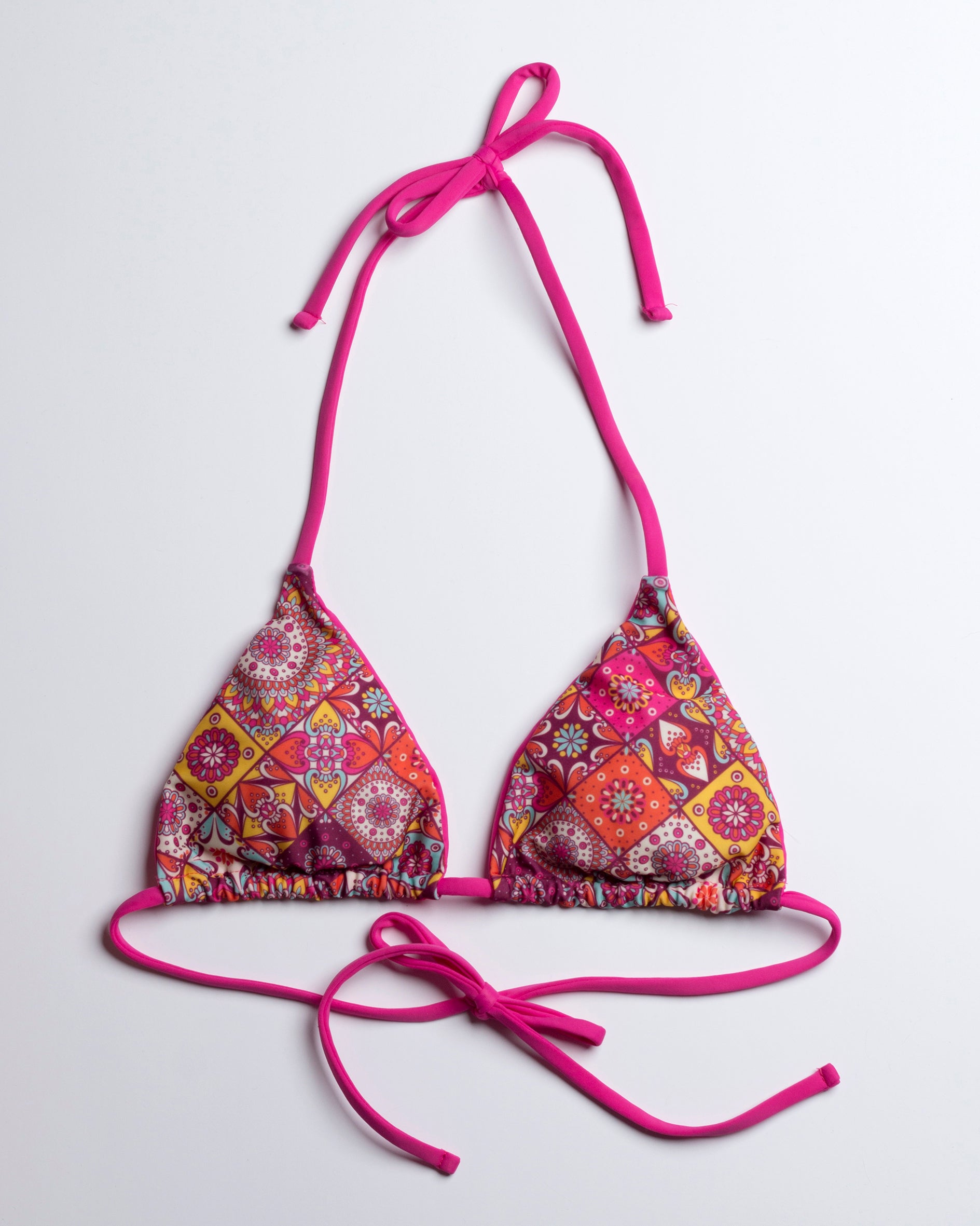 Élénk mandala mintázatú háromszög fazonú bikini felső leterített elölnézete, pink megkötőkkel, fehér háttéren 