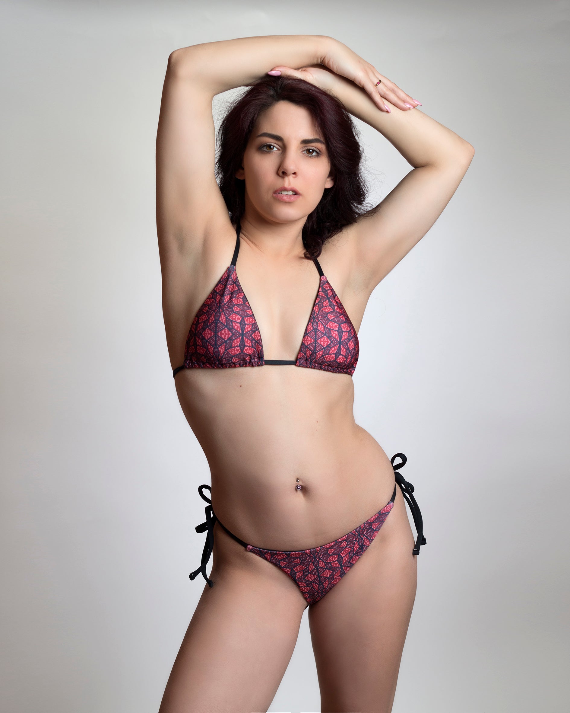 Vörös-fekete absztrakt mintás háromszög bikini felső és oldalt megkötős tanga fazonú bikini alsó fekete pántokkal, modellen, előről fotózva